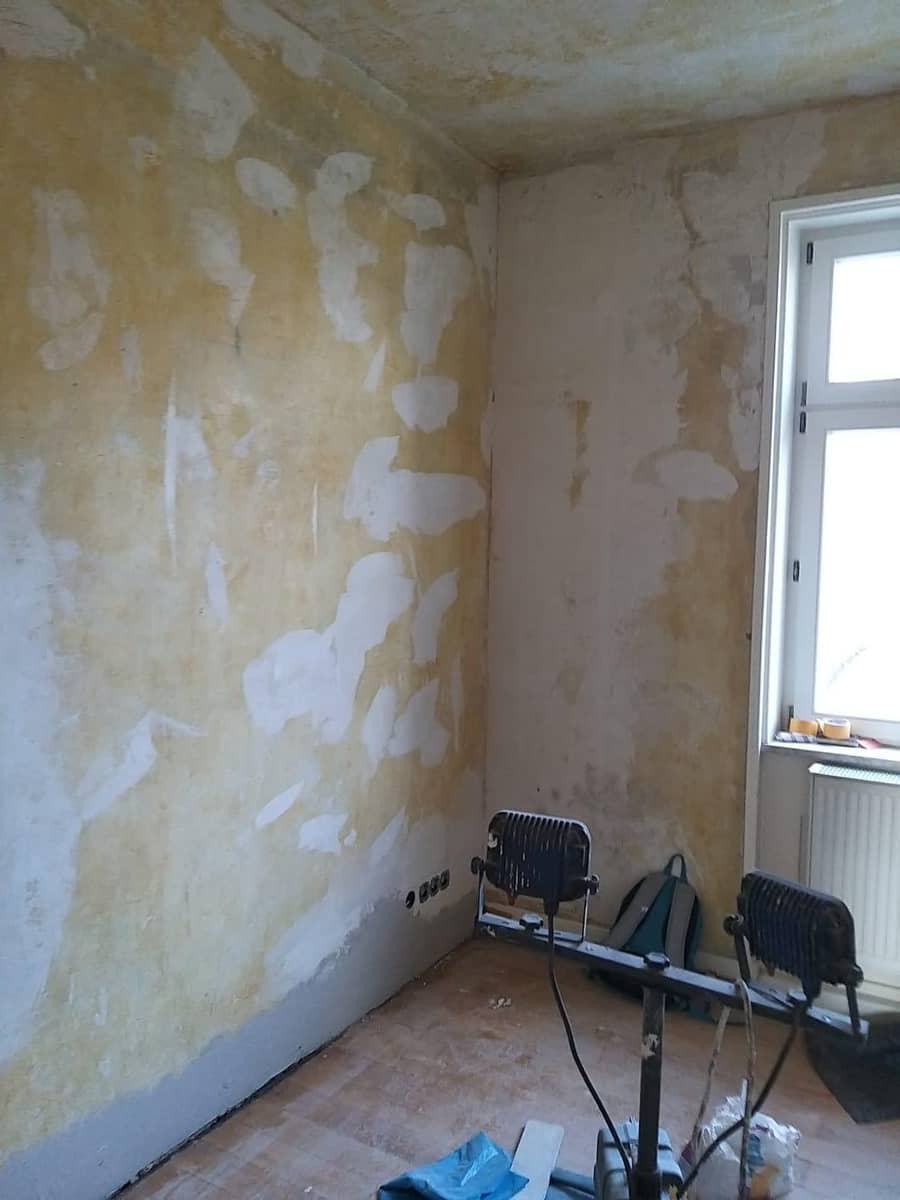 Raum in der Sanierungsphase mit gespachtelten Wänden und Arbeitsgeräten